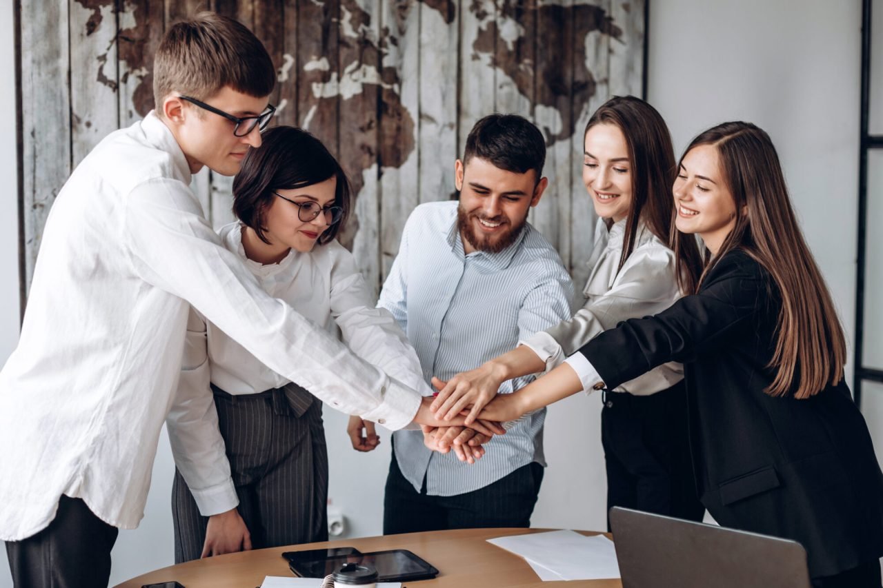 young-business-people-putting-their-hands-together-stack-of-hands-unity-and-teamwork-concept-e1699882261103
